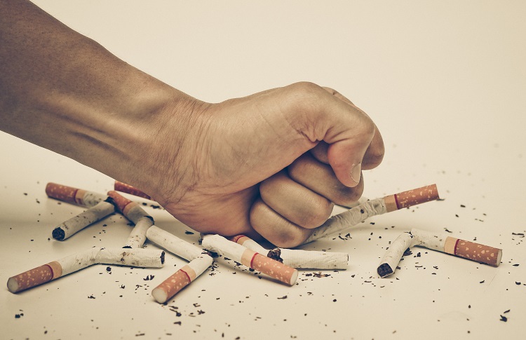 Miehen käsi tuhoaa savukkeet, höyrystäminen voi auttaa tupakoinnin lopettamisessa
