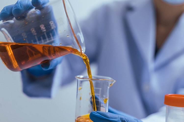 A gloved hand pouring 10-OH-HHCP distillate from a container