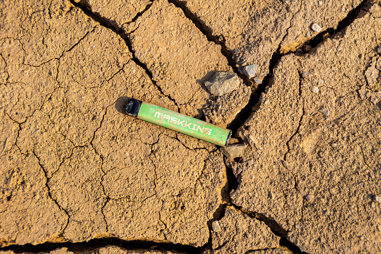 En brugt vaporizer ligger på revnet jord, hvilket er skadeligt for miljøet